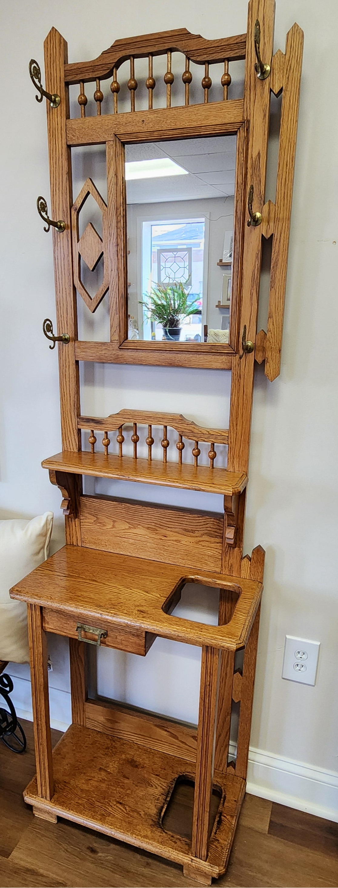 Wooden hall tree with mirror and shelves in a room setting.