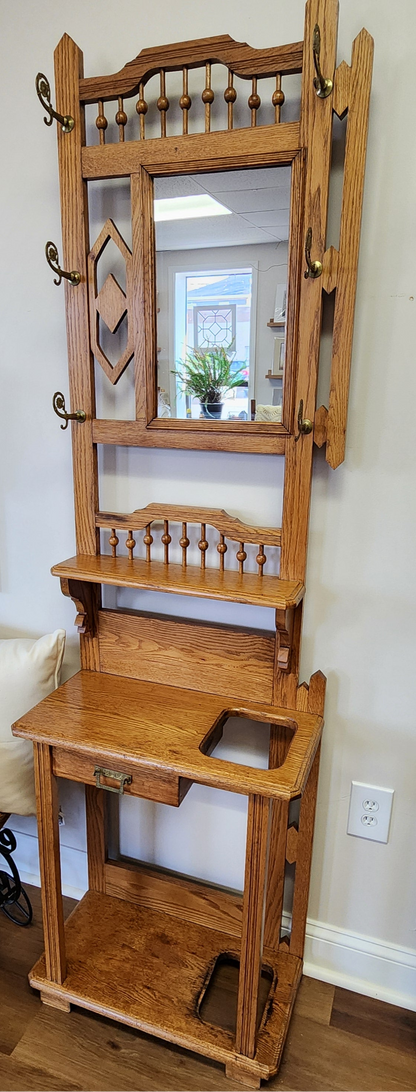 Wooden hall tree with mirror and shelves in a room setting.